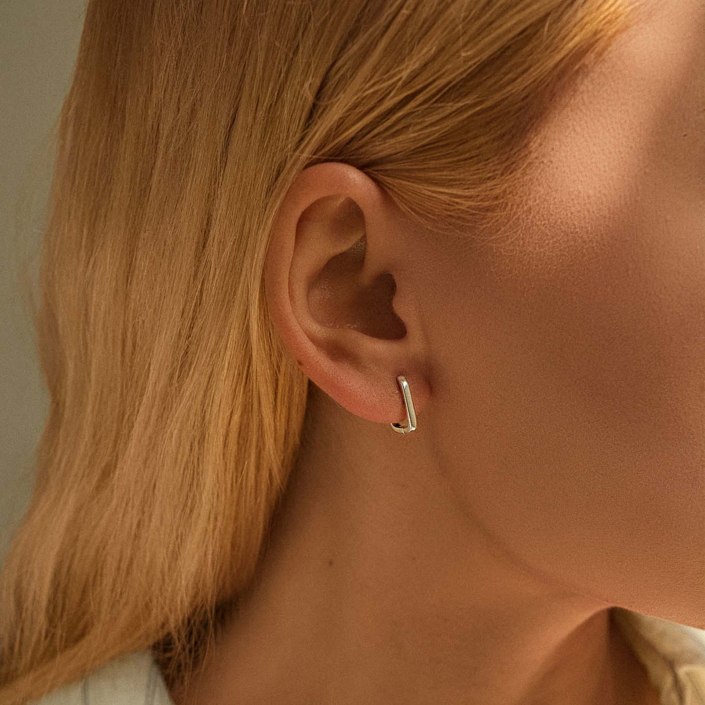 Model wearing minimalist rectangular silver huggie earrings