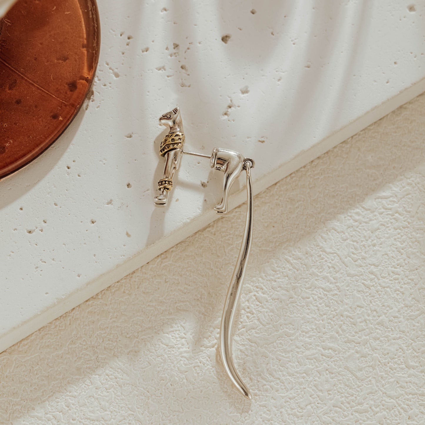Cat dangle earring laid on stone surface showing detailed feline design