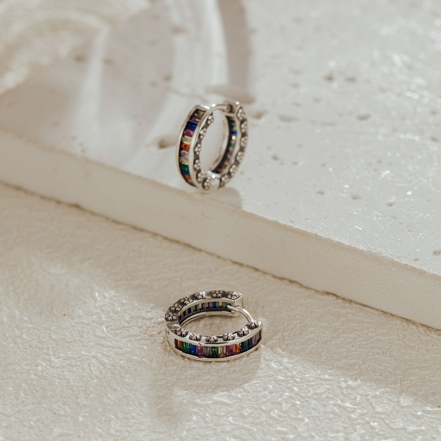 Sterling silver rainbow baguette huggie earrings on display card