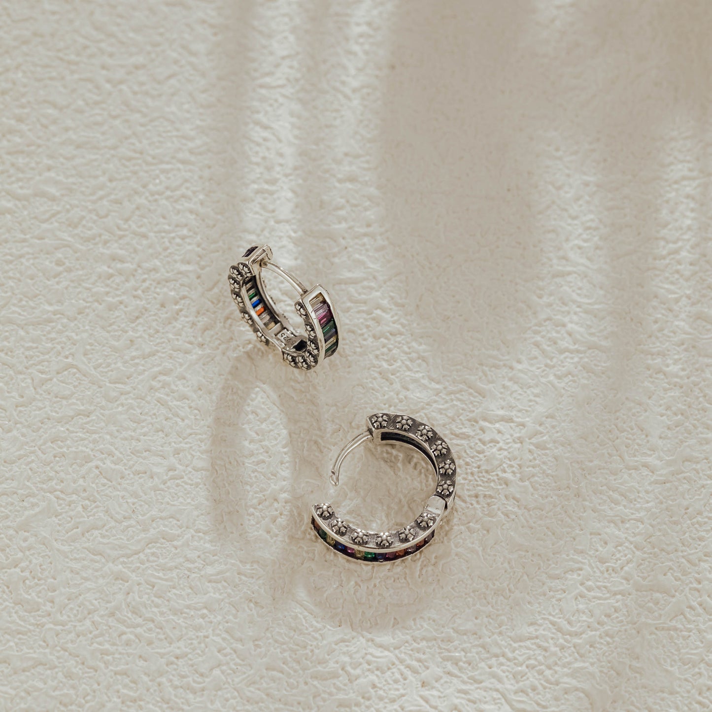 Pair of rainbow baguette huggie earrings with hinged clasp open