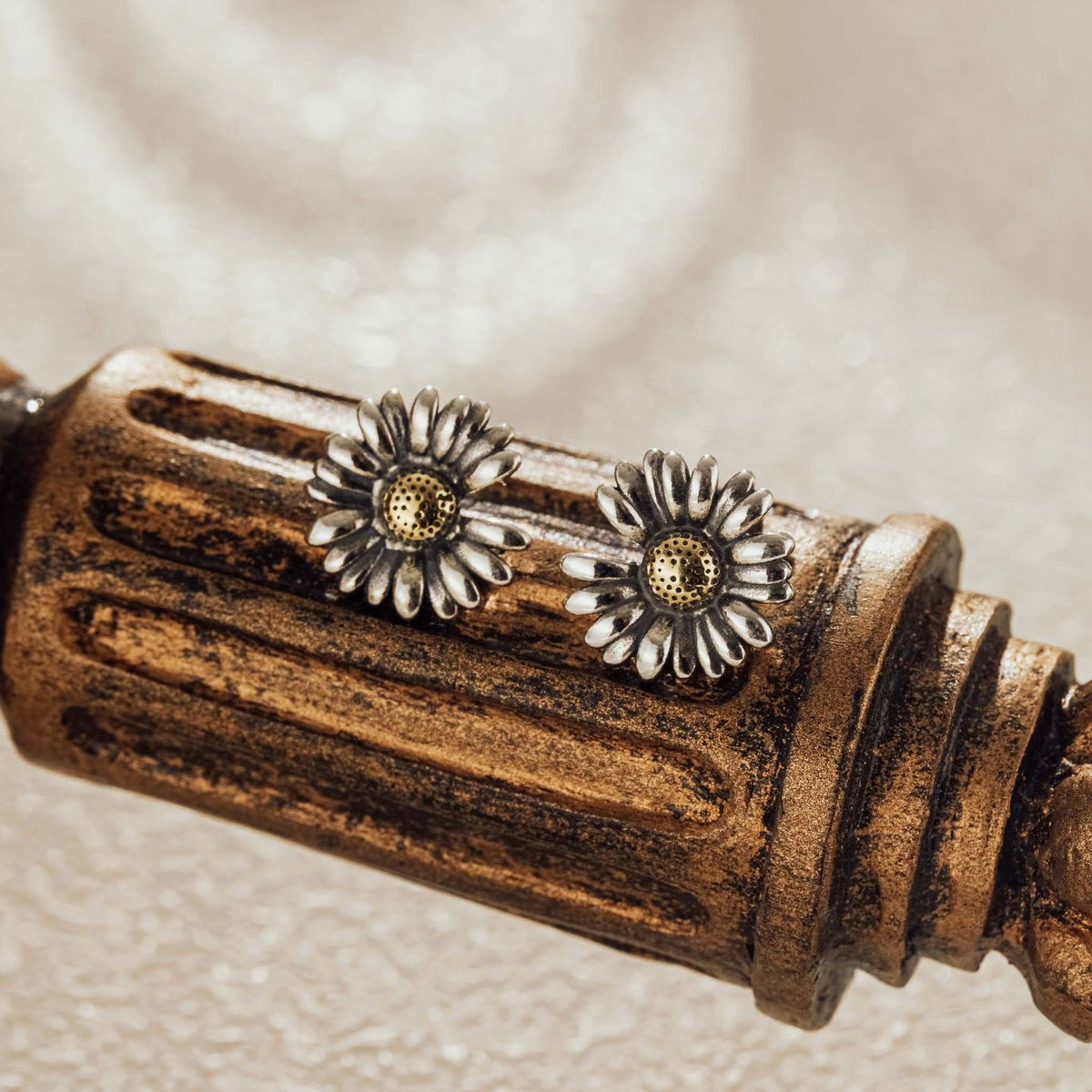 Vintage-style daisy silver earrings displayed on a rustic wooden accent