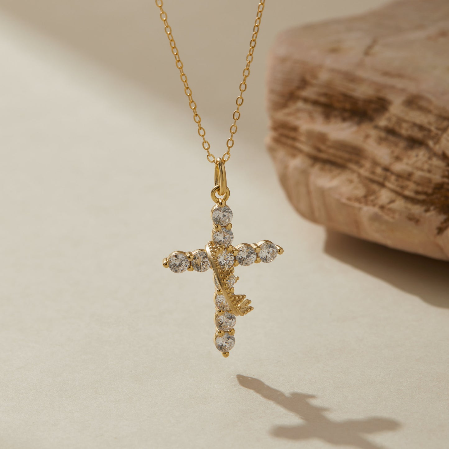 Gold crown cross pendant close-up on stone background