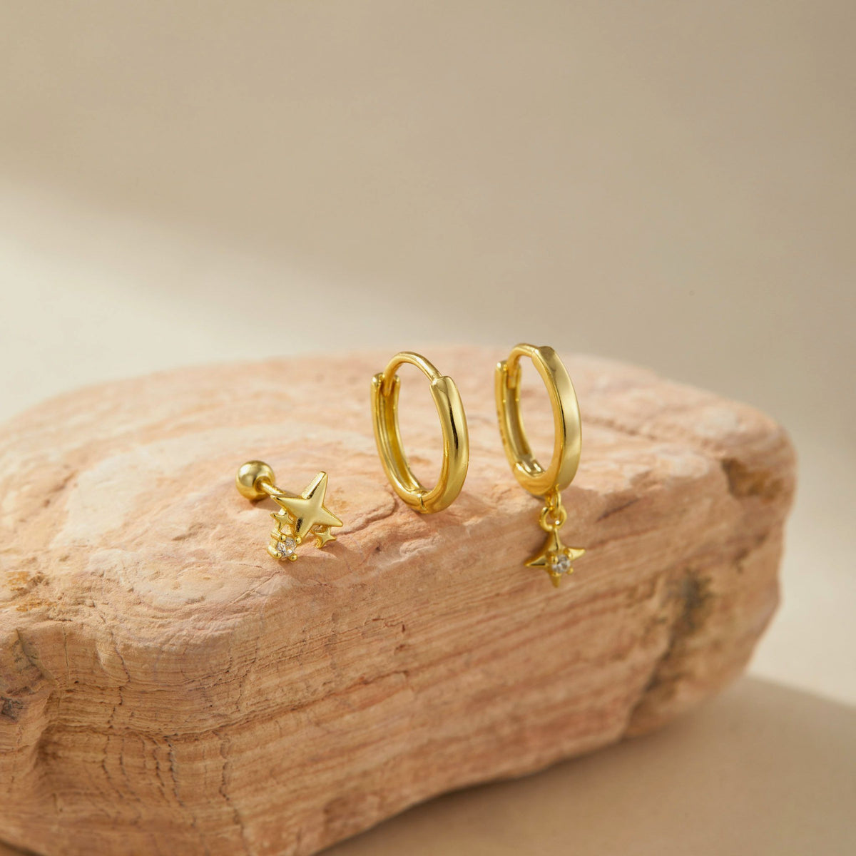 Gold plated star earring set on sandstone, star stud beside a plain and a star drop huggie