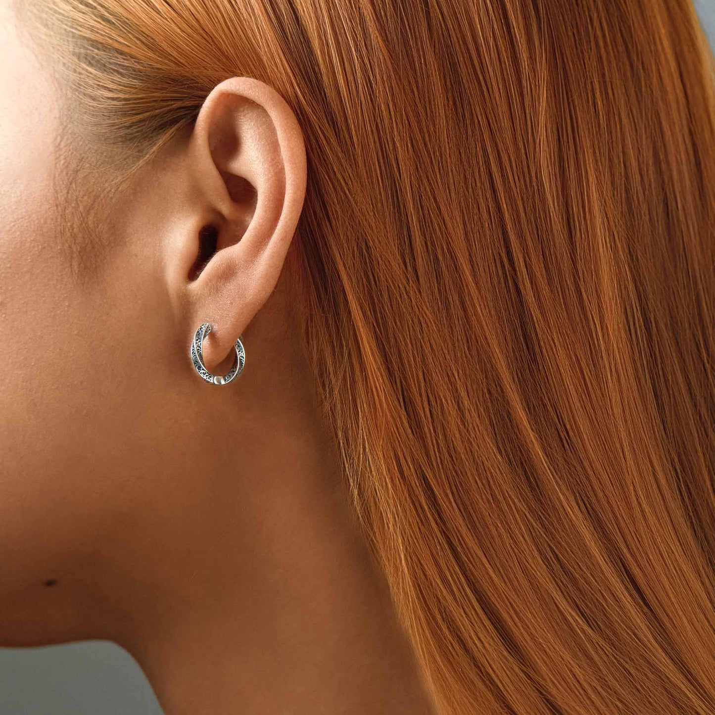 Engraved oxidized silver huggie earrings worn on model