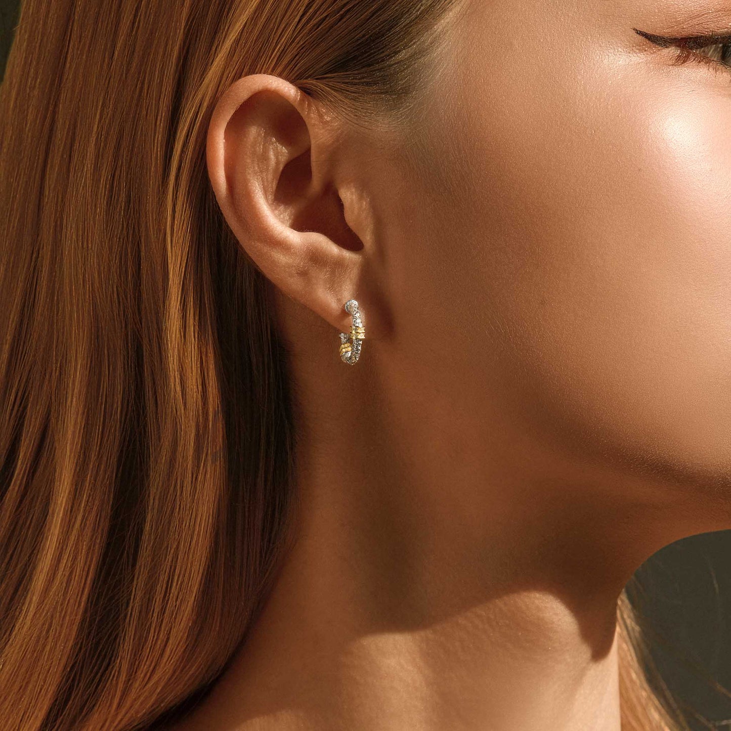 Two-tone silver and gold hoop earrings worn on model