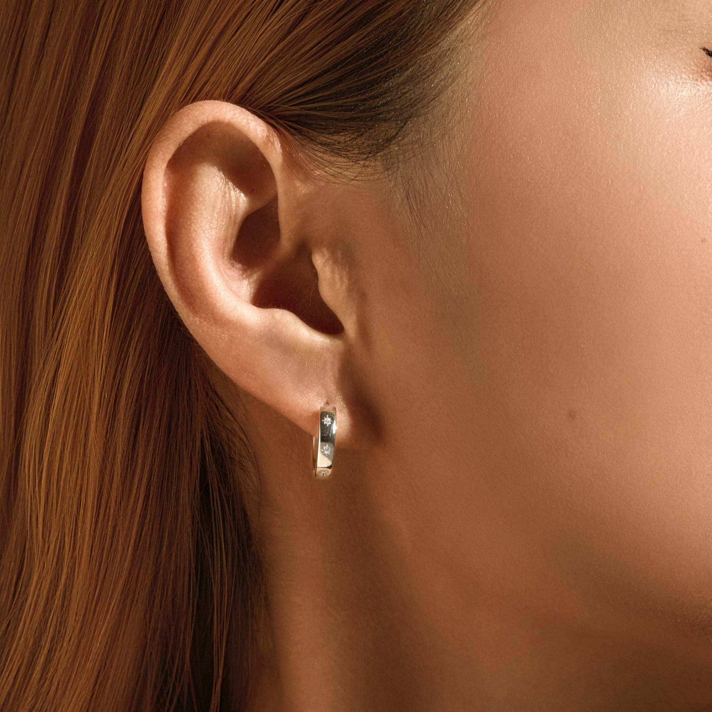 Lifestyle photo – engraved star sterling silver huggie worn on ear