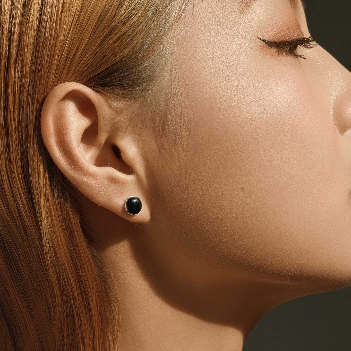 Lifestyle photo – black CZ stud earrings worn on ear (~0.3 in diameter)