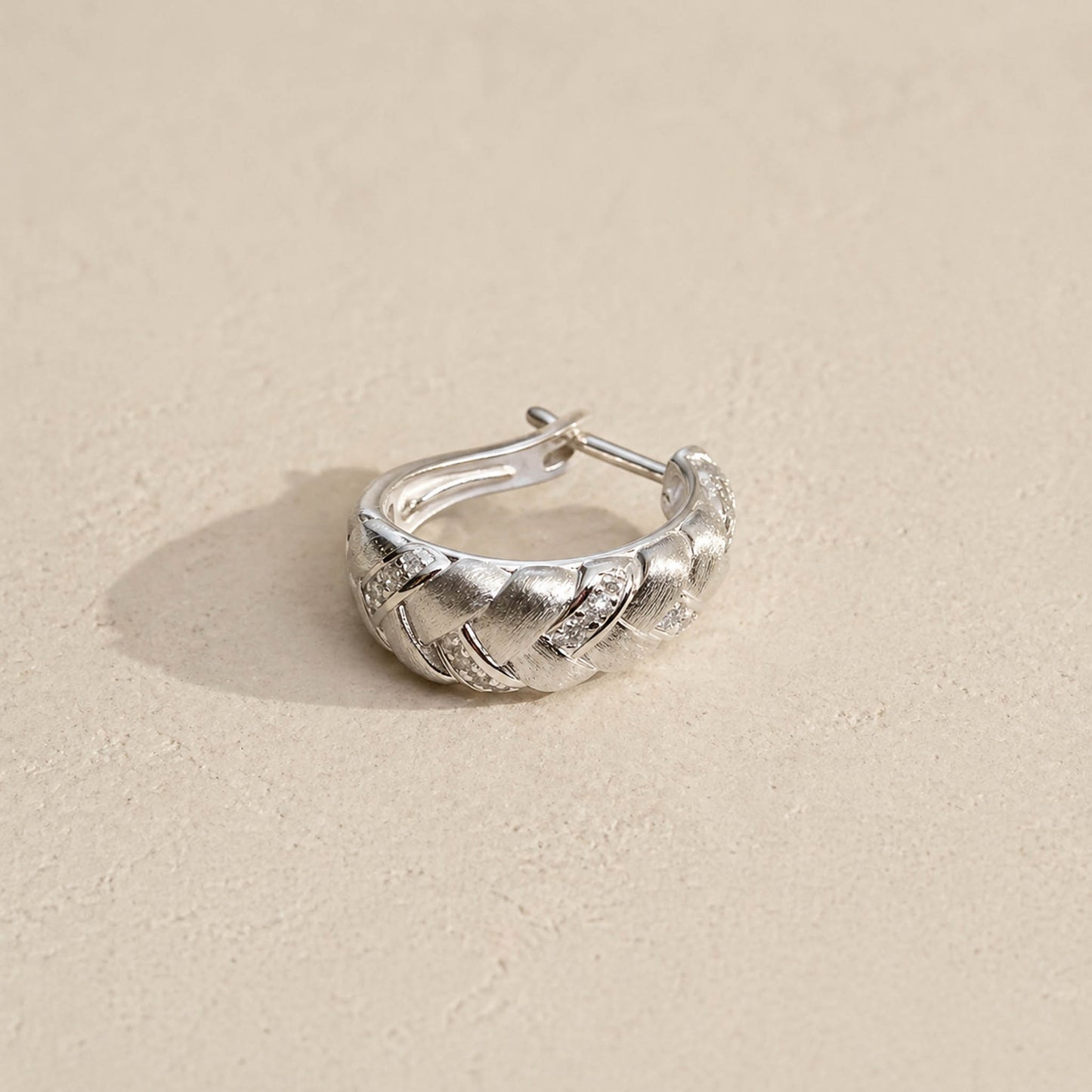 Brushed sterling silver braided huggie hoop earring with pavé accents and hinged closure, side angle