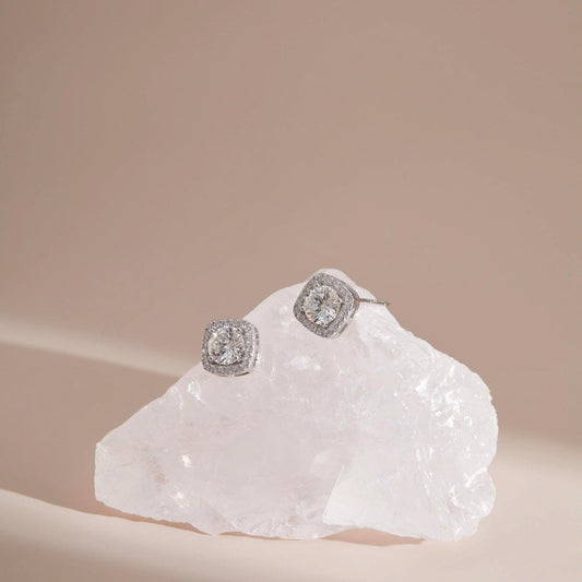 Flat lay on quartz — White moissanite halo stud earrings with halo sparkle.