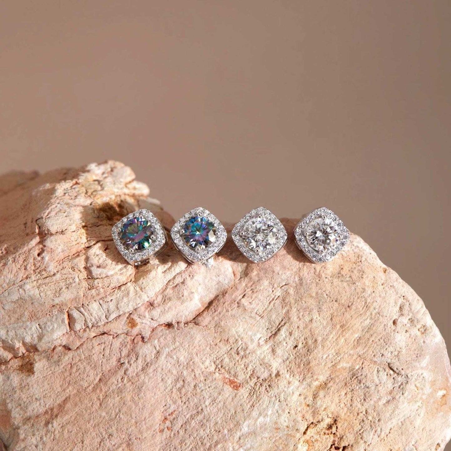 Flat lay on stone — Moissanite square halo stud earrings, sterling silver, white & rainbow blue stones.