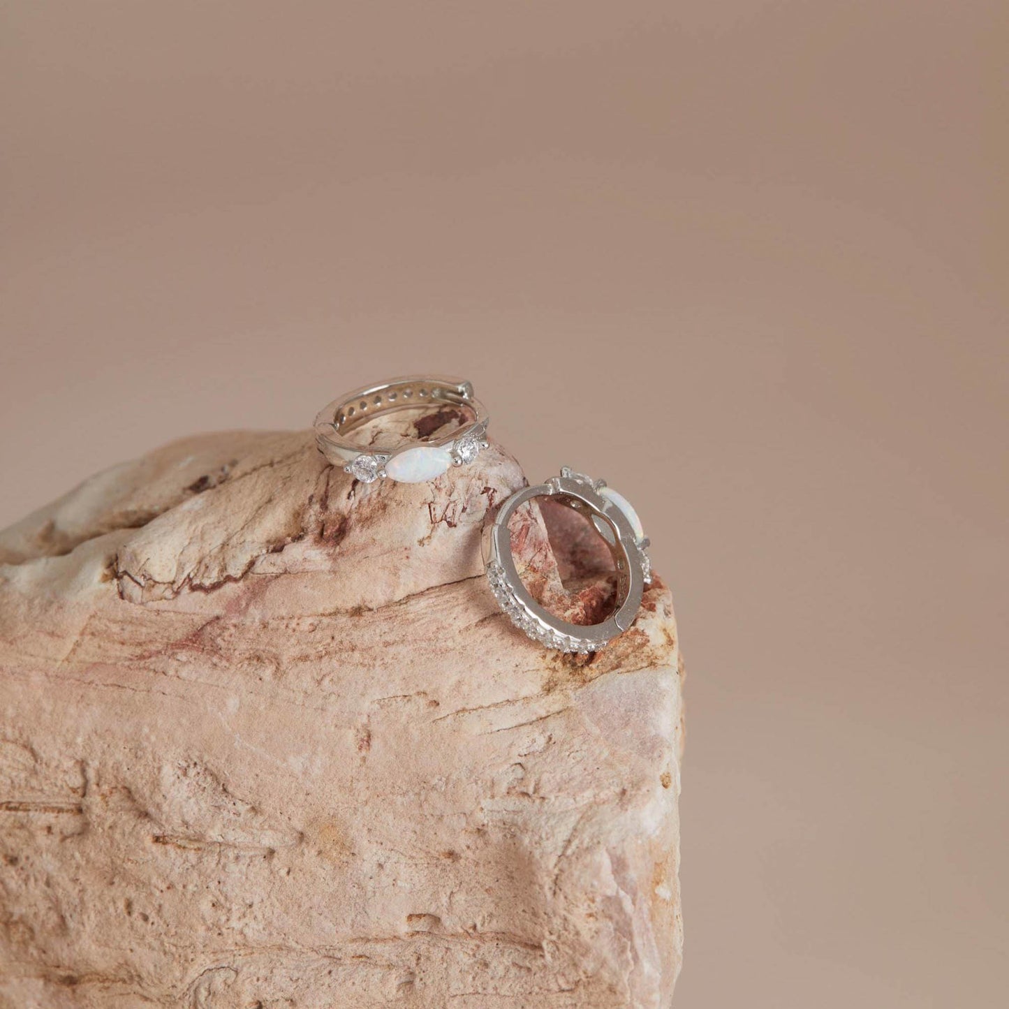 White gold opal huggies displayed on stone surface