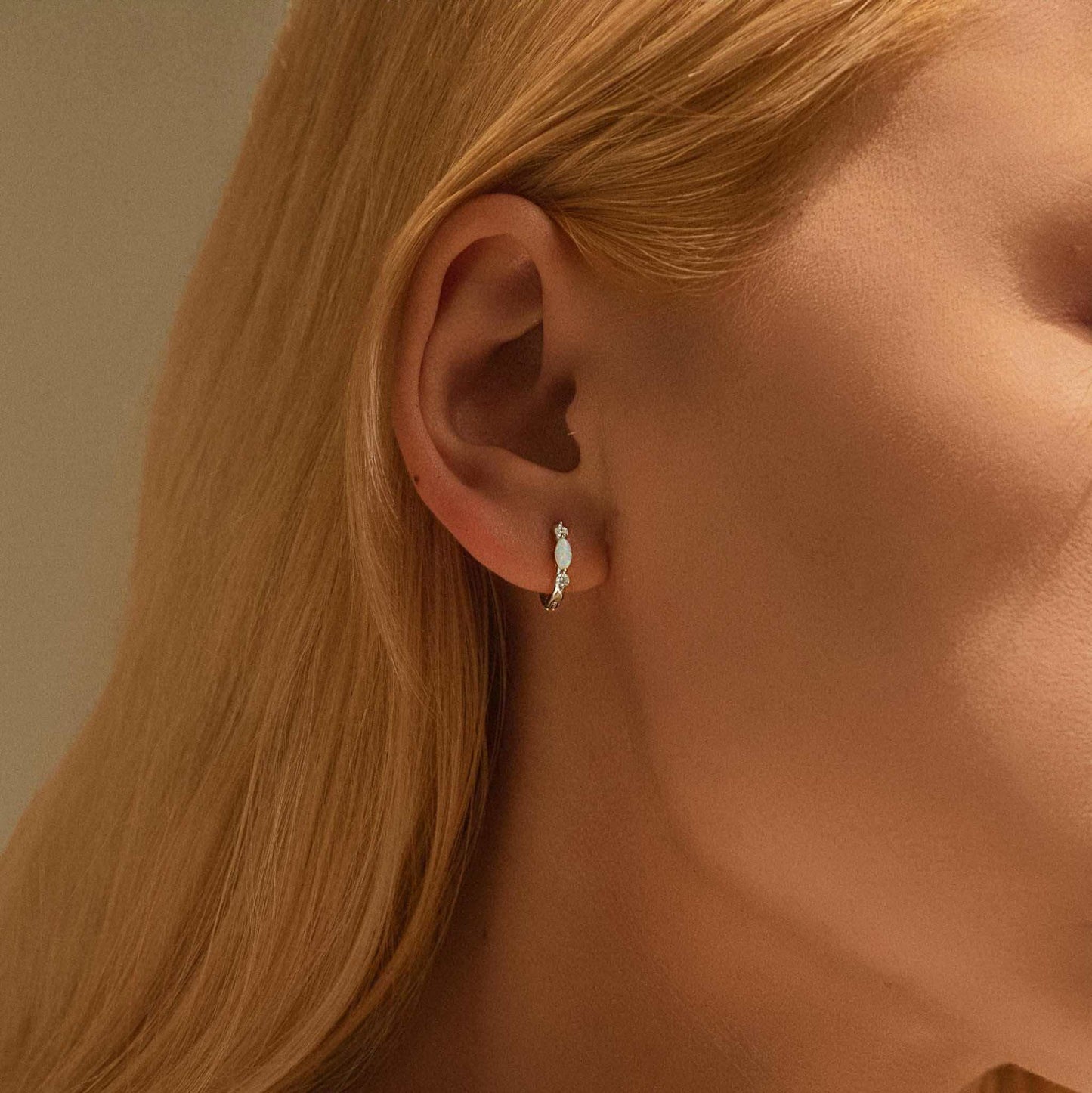 Model wearing white gold opal huggie hoop earrings