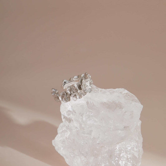 Vintage sterling silver floral adjustable ring displayed on crystal
