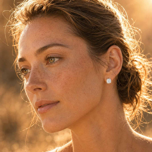 Woman wearing 1ct round cut white moissanite halo stud earring in sterling silver, side profile in sunlight