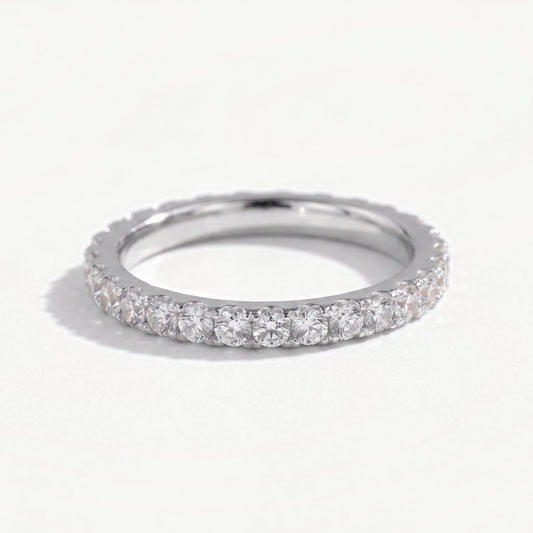 Sterling silver moissanite eternity ring leaning on a near white ground, full pavé of claw set stones