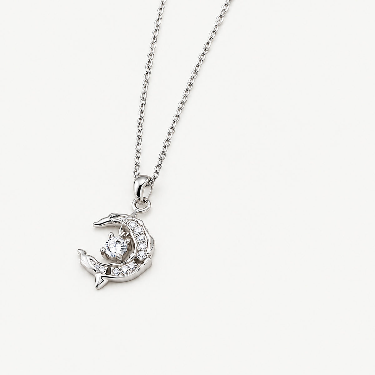 Sterling silver crescent moon dolphin pendant on a cable chain, two dolphins framing a swinging round clear stone