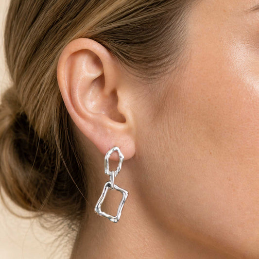 Woman wearing sterling silver sculptural dangle earring, side profile with hair pulled back