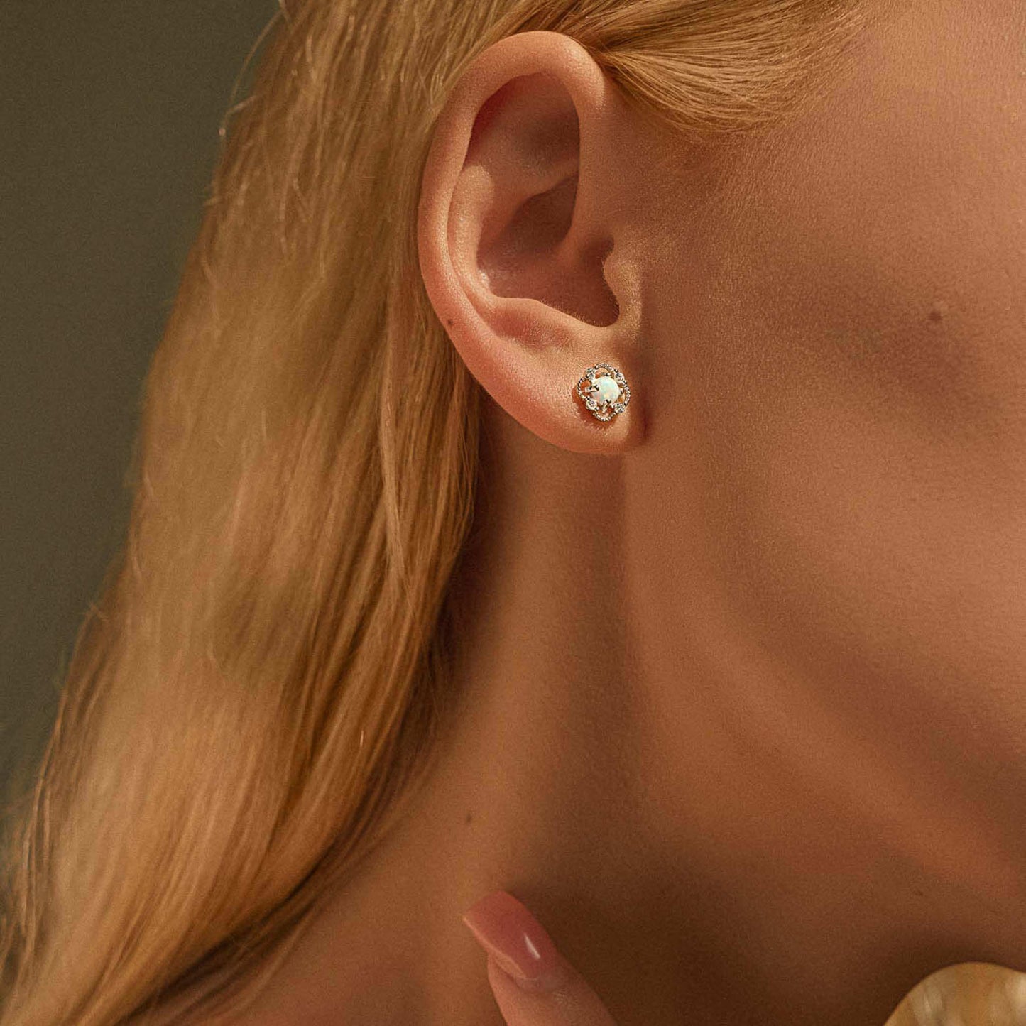 Close-up of silver opal floral stud earring worn on ear for scale.