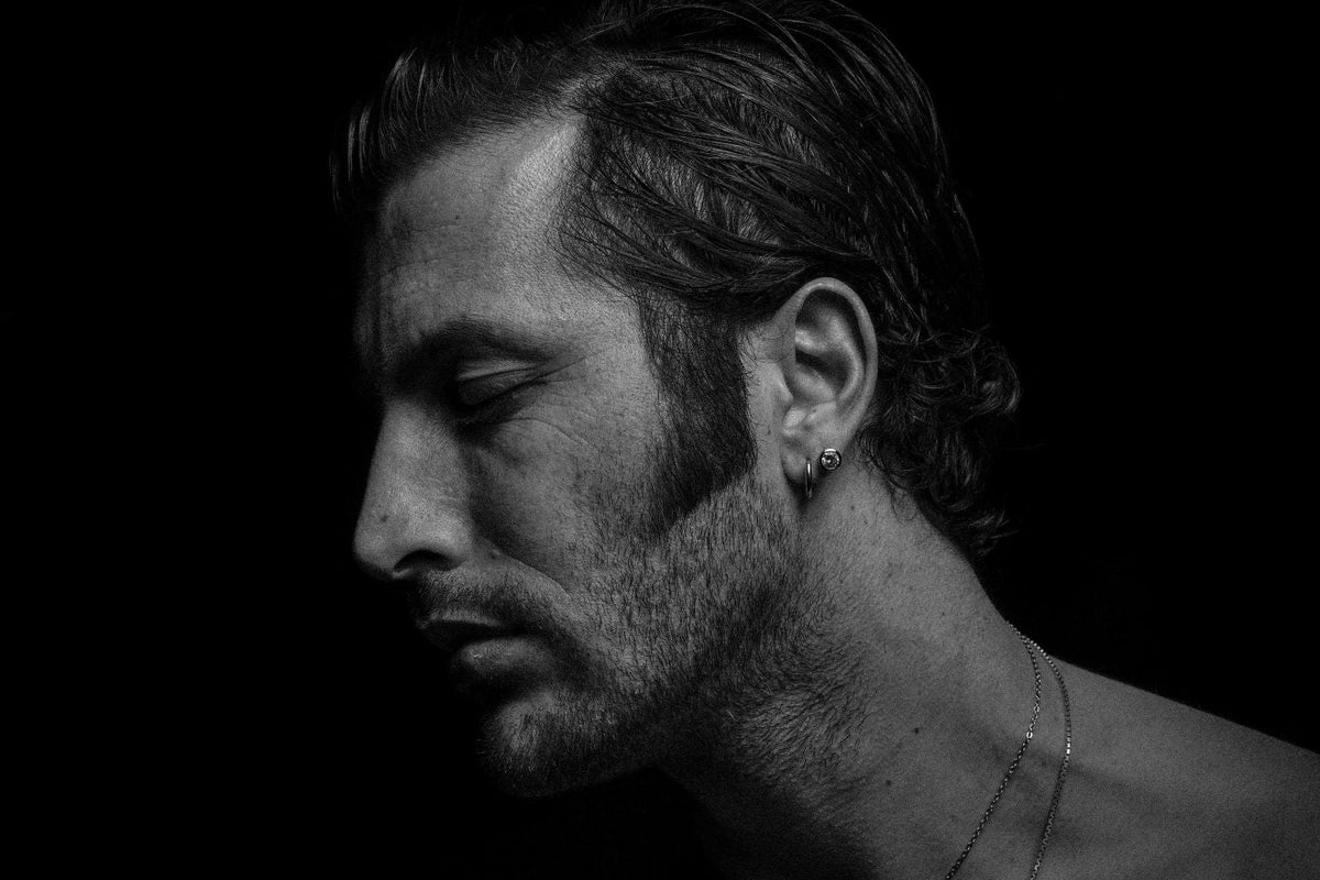 lack and white portrait of a man wearing sterling silver earrings and necklace, highlighting modern men’s minimalist jewelry style.