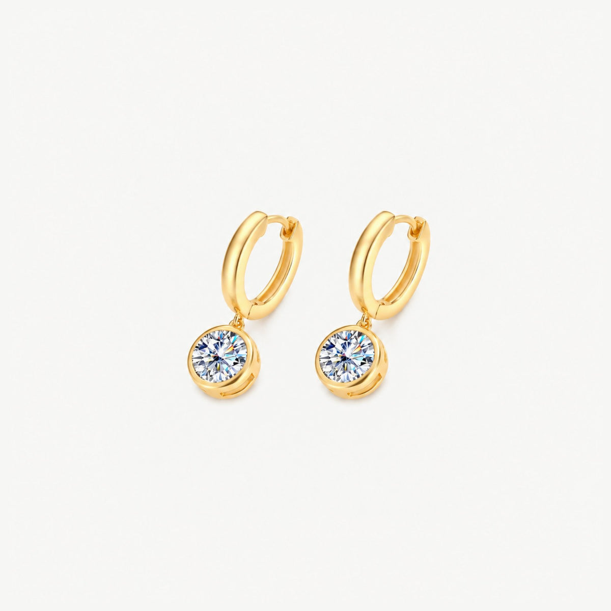 Gold moissanite drop huggie earrings turned at an angle, showing the hinged hoops and the open sides of each bezel