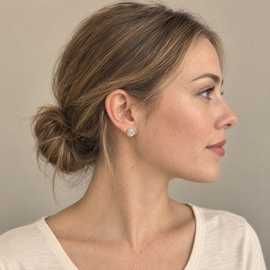 Woman in side profile wearing a white 1ct moissanite halo stud earring in sterling silver, hair in a low bun