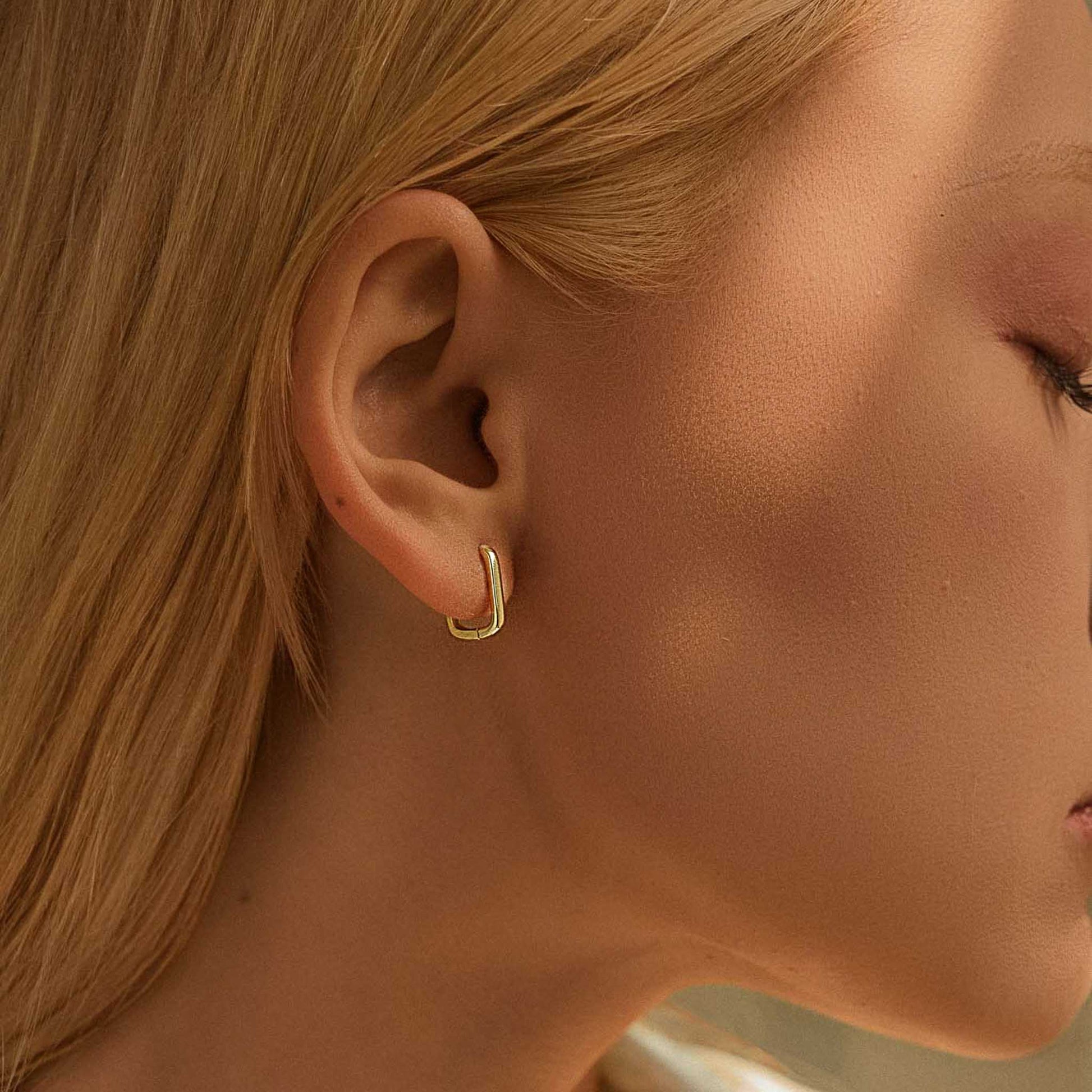 Model wearing minimalist rectangular gold color silver huggie earrings