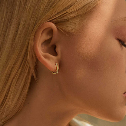 Model wearing minimalist rectangular gold color silver huggie earrings