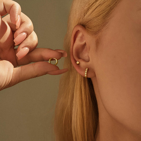 Model wearing gold plated opal stud and opal huggie hoop in a stacked ear, holding the plain huggie