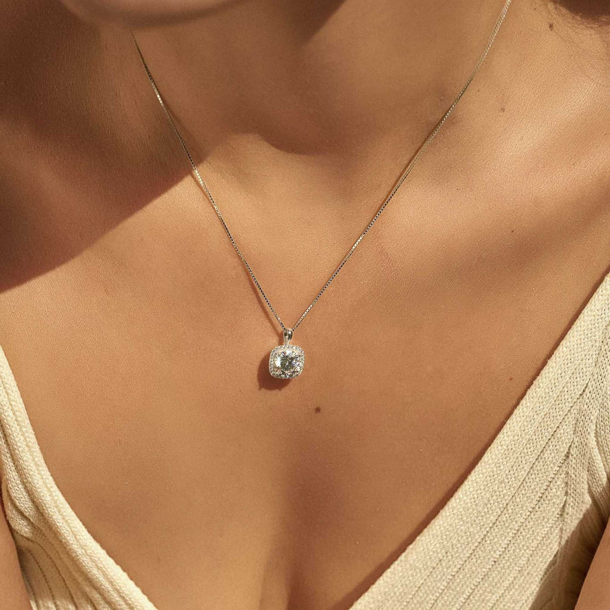 Woman wearing moissanite square halo pendant necklace, close-up on chest