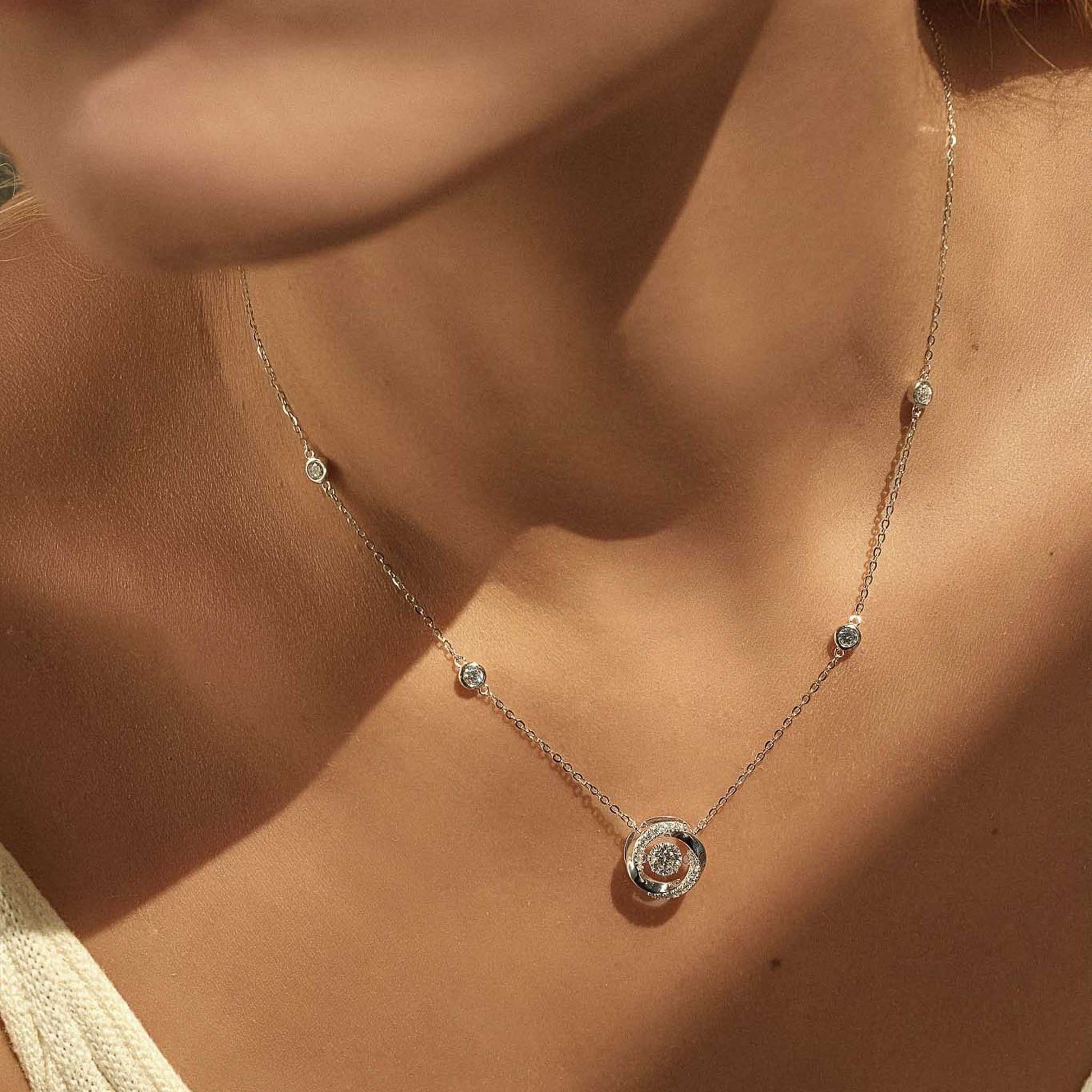 Woman wearing sterling silver moissanite spiral pendant necklace, close-up on chest