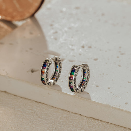 Rainbow baguette huggie earrings in sterling silver, close-up with multicolor stones