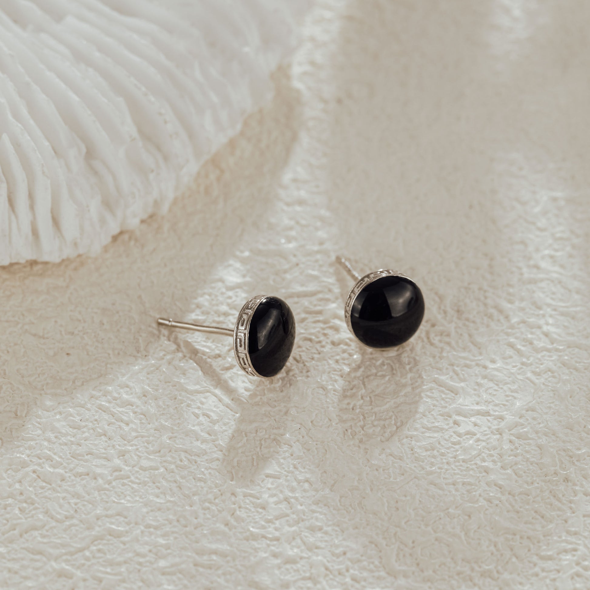 Close-up of black CZ stud earrings on textured background
