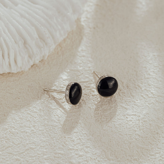 Close-up of black CZ stud earrings on textured background