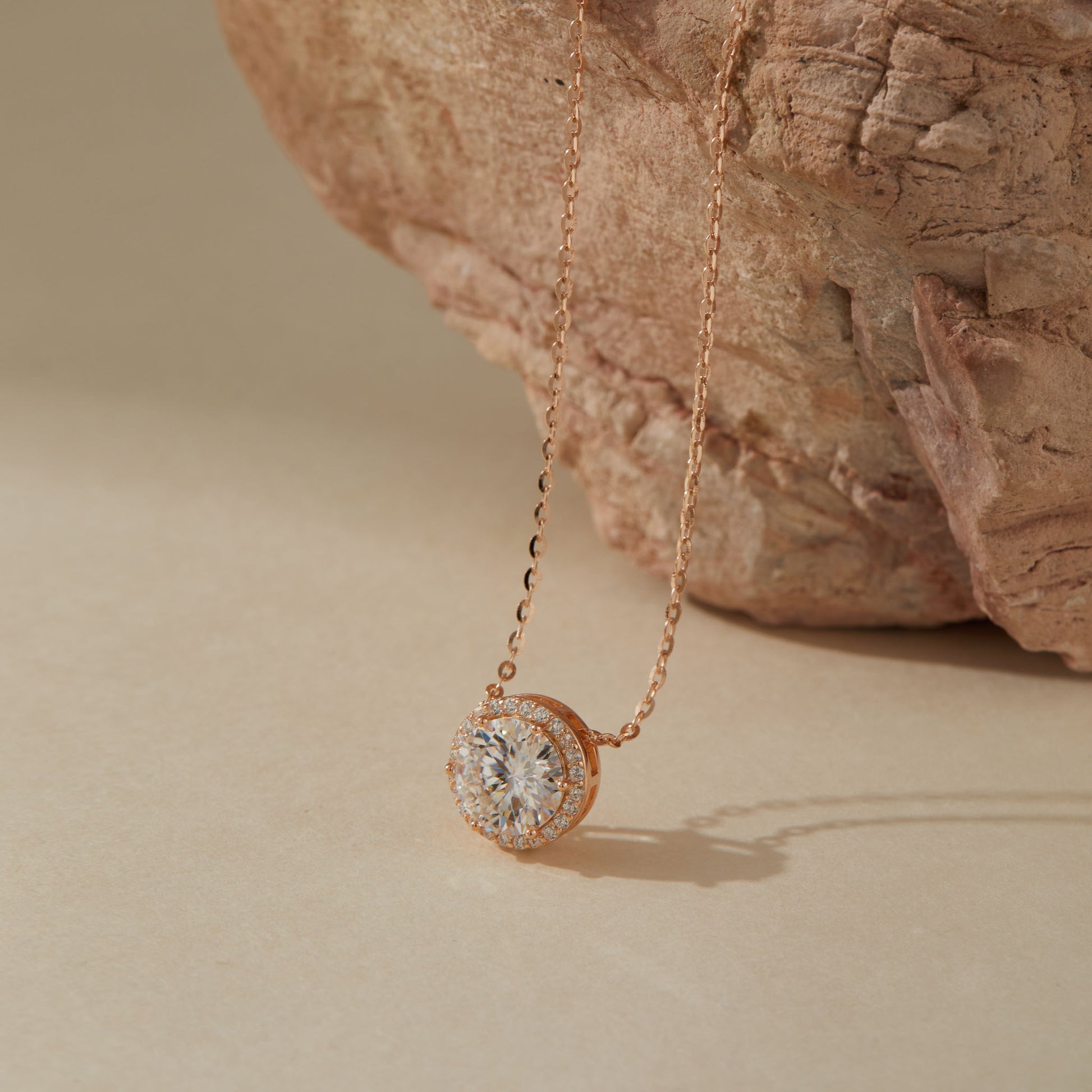 Rose gold moissanite pendant close-up showing halo setting detail against stone