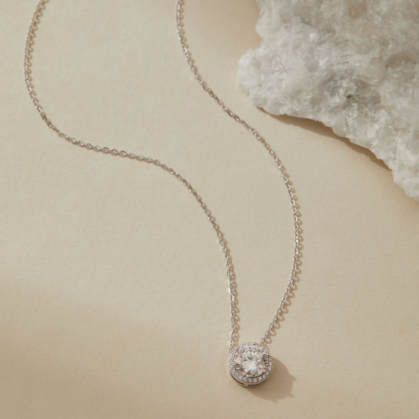 Sterling silver moissanite halo pendant necklace with quartz crystal in background

