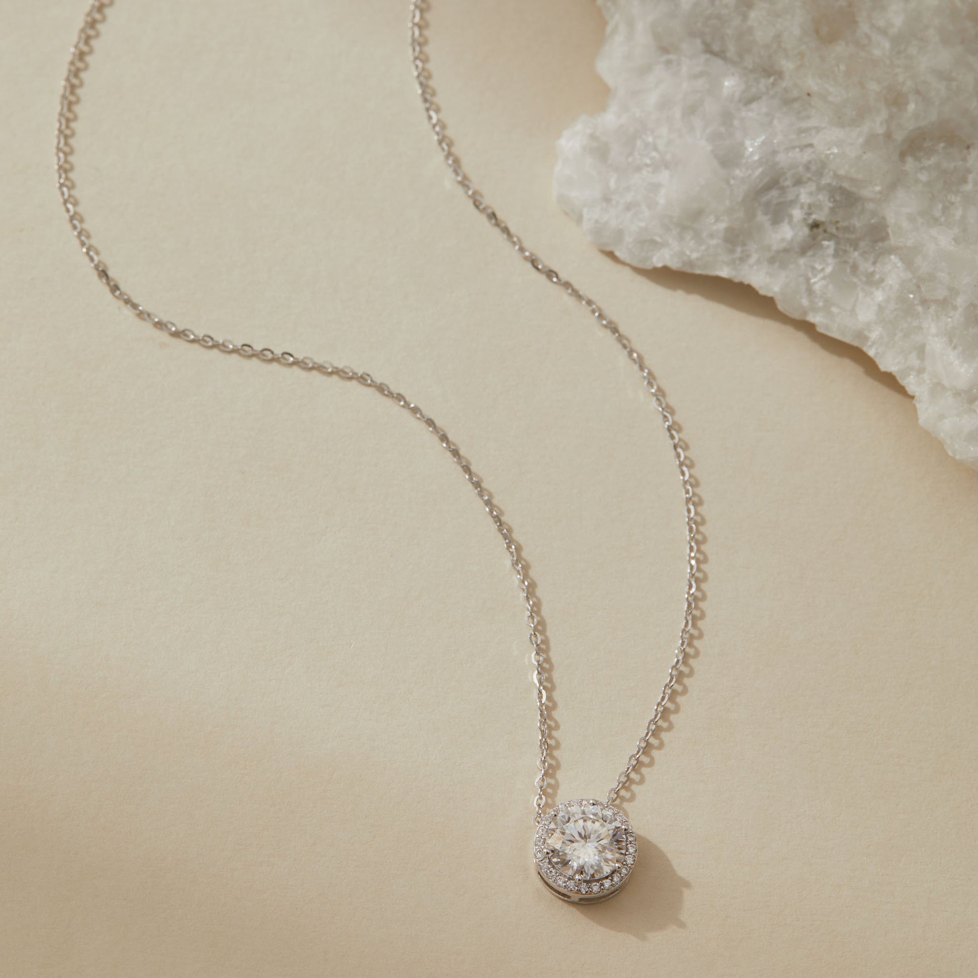 Sterling silver moissanite halo pendant necklace with quartz crystal in background

