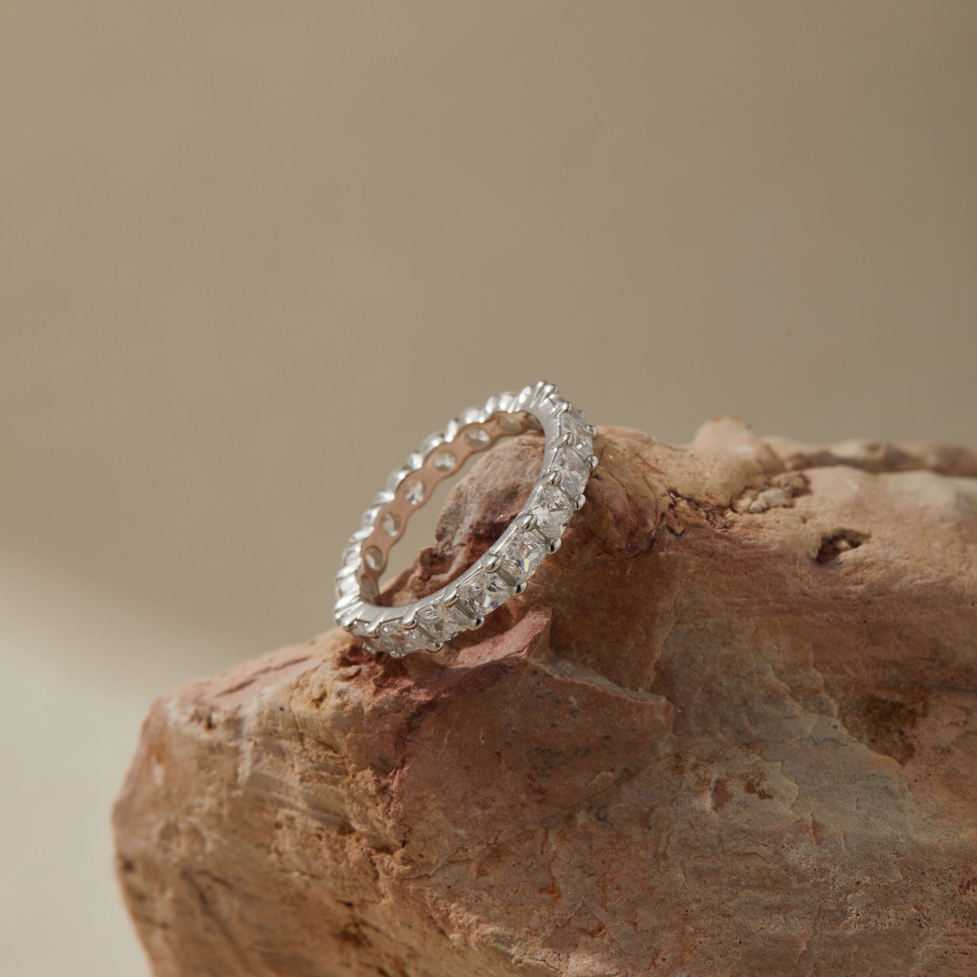 Round and princess-cut silver eternity ring styled on a neutral background