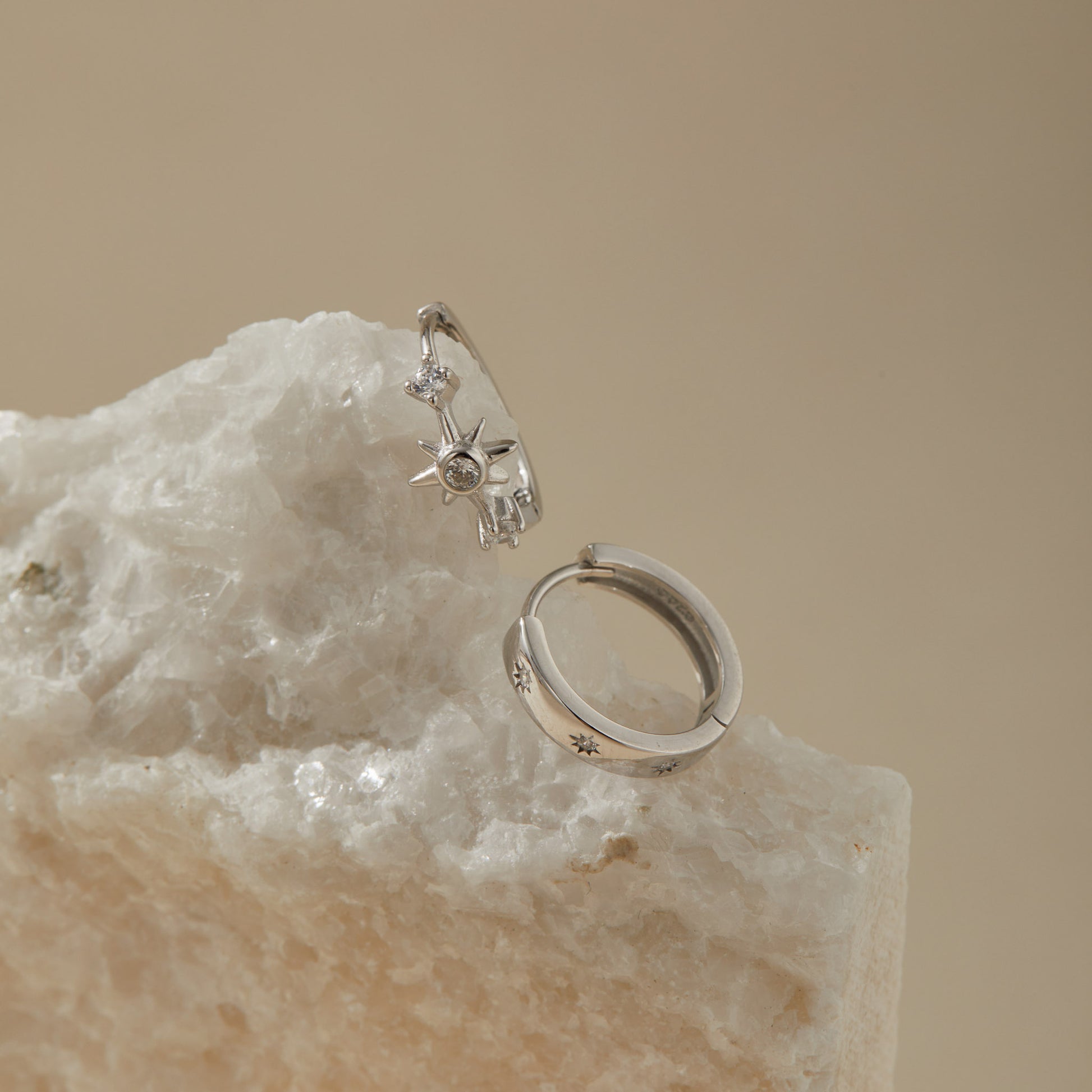 Starburst huggie earring set on quartz surface, polished sterling silver