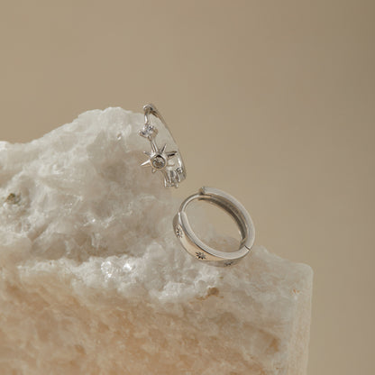 Starburst huggie earring set on quartz surface, polished sterling silver