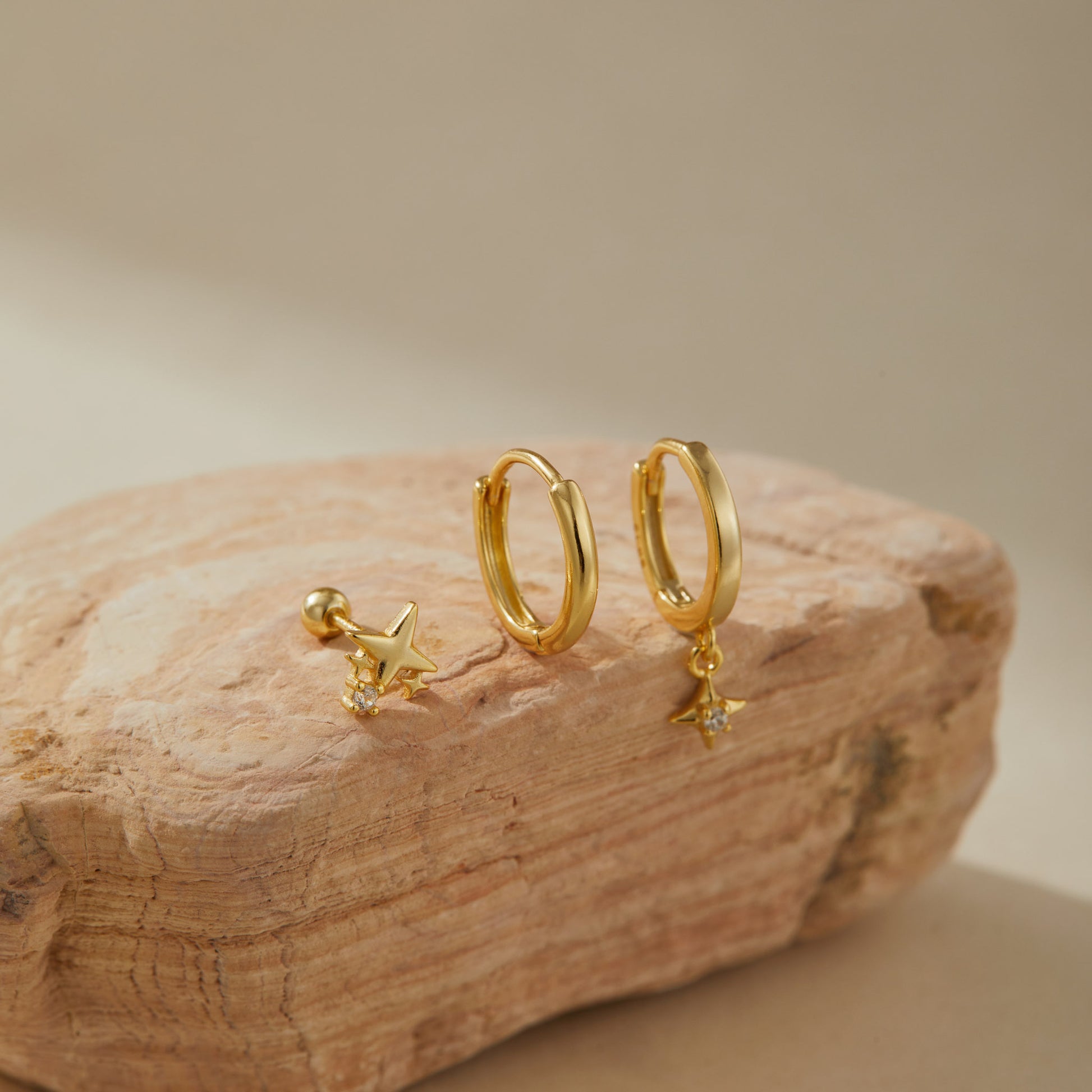 Gold plated star earring set on sandstone, star stud beside a plain and a star drop huggie
