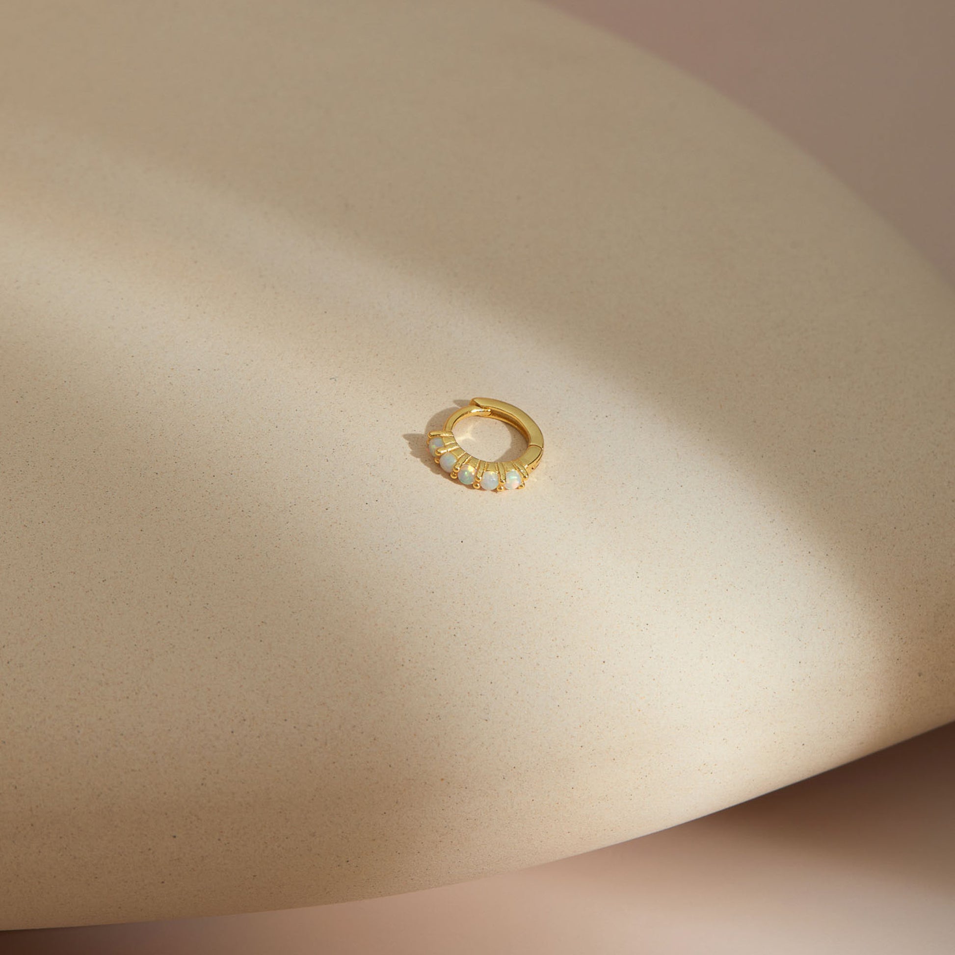 Gold plated opal huggie hoop earring with five round opals set in a row along the front of the band