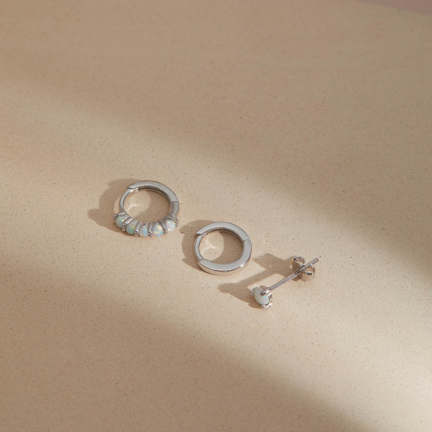 Sterling silver opal earring set of three, opal huggie hoop, plain huggie hoop and opal stud on beige