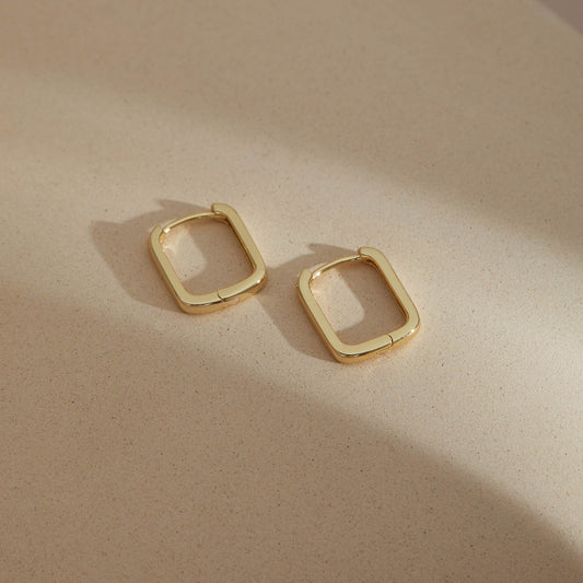 Gold color rectangular S925 huggie earrings displayed on neutral background