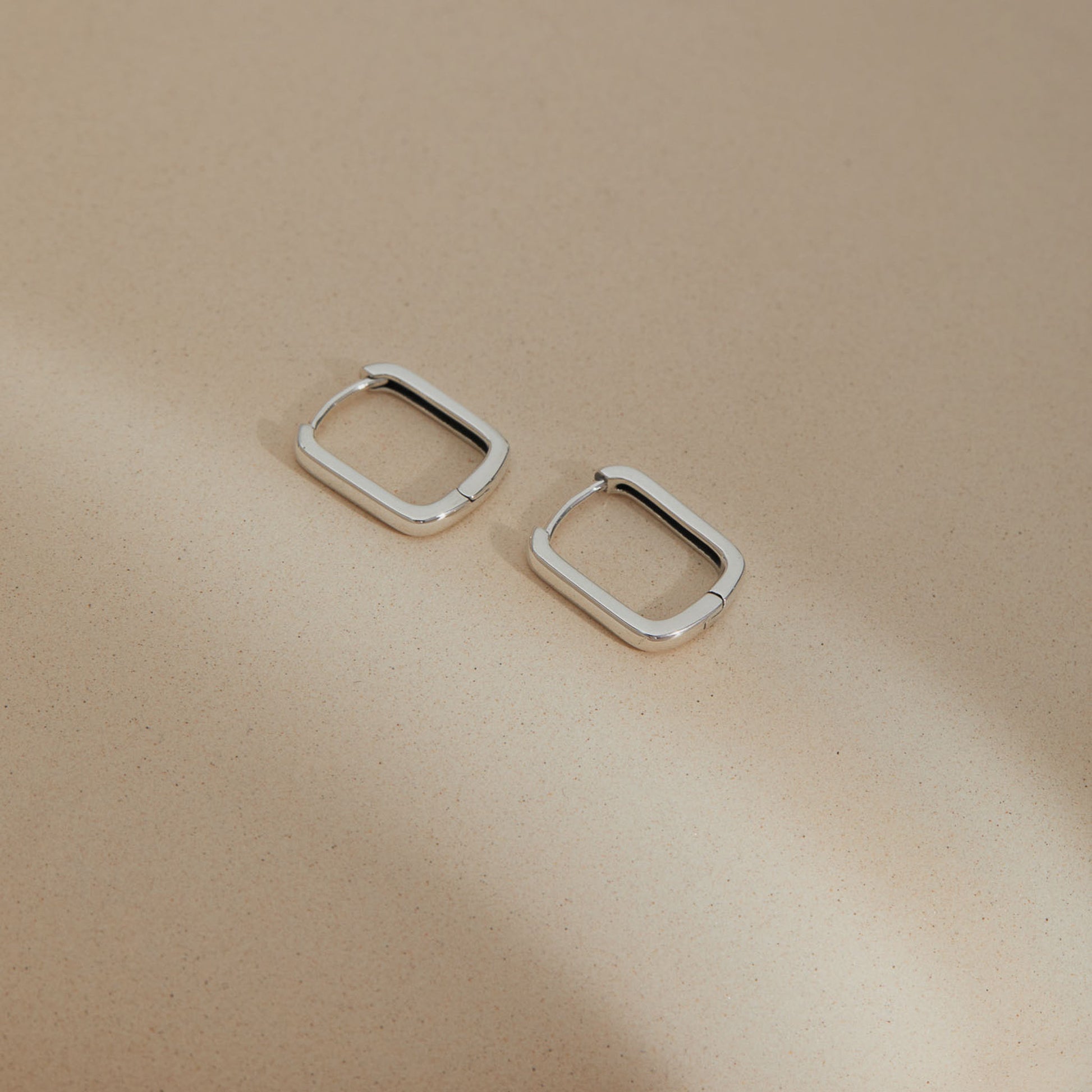 Rectangular S925 huggie earrings displayed on neutral background