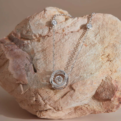 Sterling silver moissanite dancing stone spiral pendant on sandstone, station chain visible