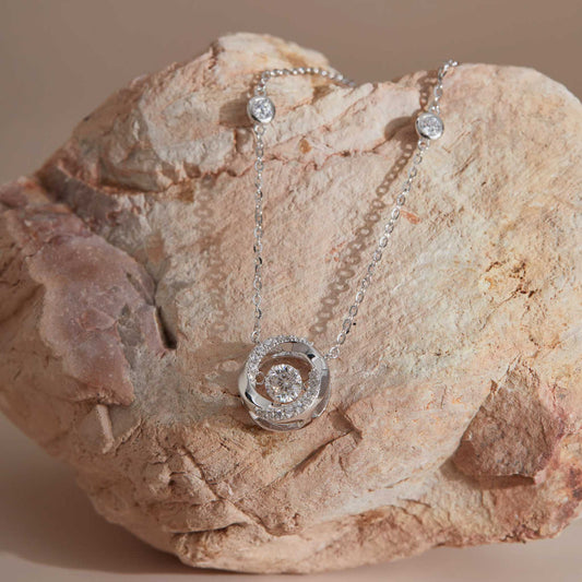 Sterling silver moissanite dancing stone spiral pendant on sandstone, station chain visible