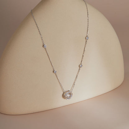 Moissanite spiral station necklace full length on curved display, showing bezel-set chain accents