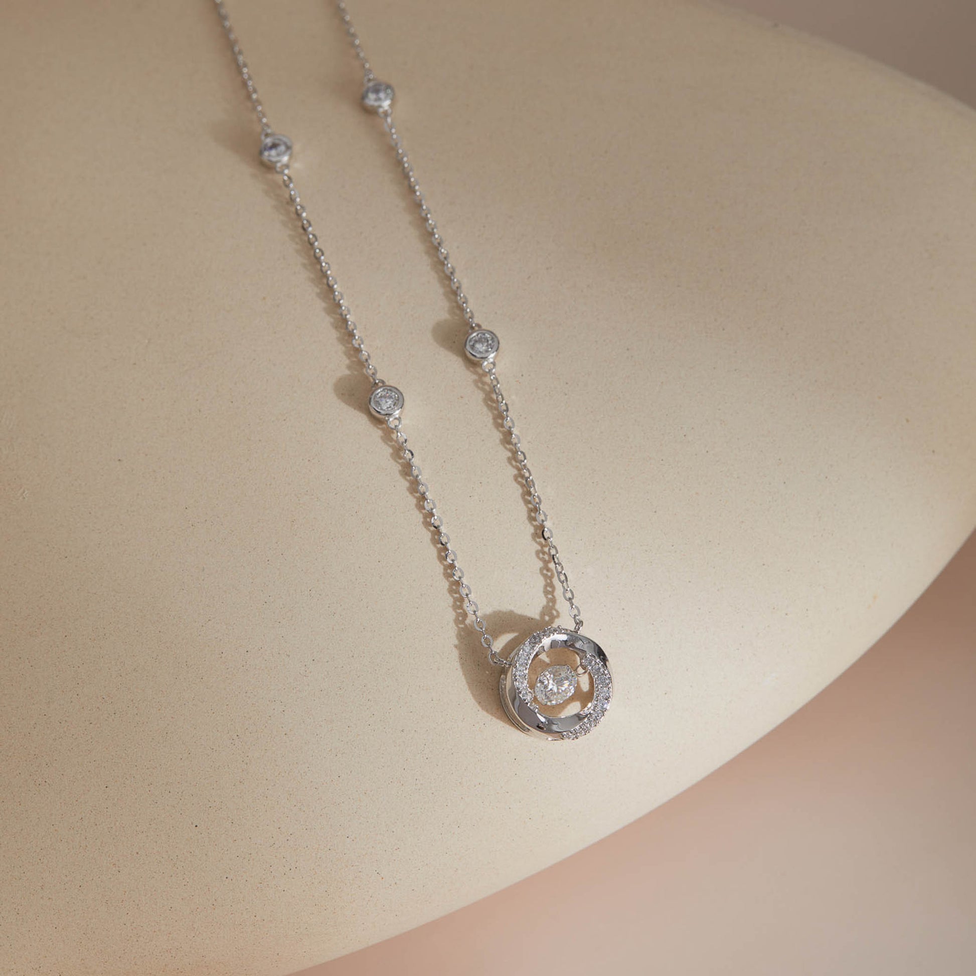 Moissanite spiral pendant and station chain close-up on curved surface