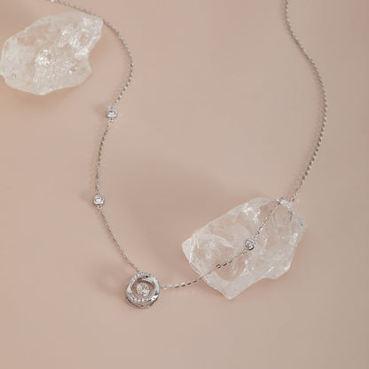 Sterling silver moissanite dancing stone necklace with station chain, draped over crystal quartz