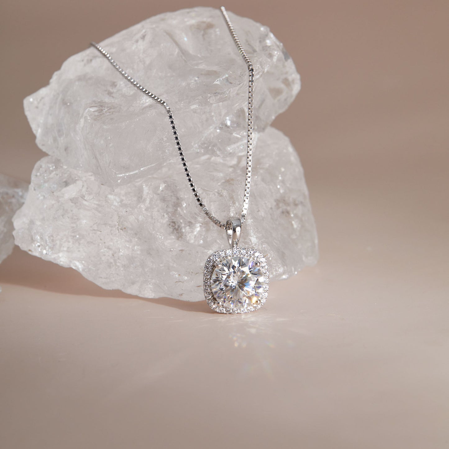 Close-up of moissanite cushion halo pendant showing round center stone and square setting against crystal